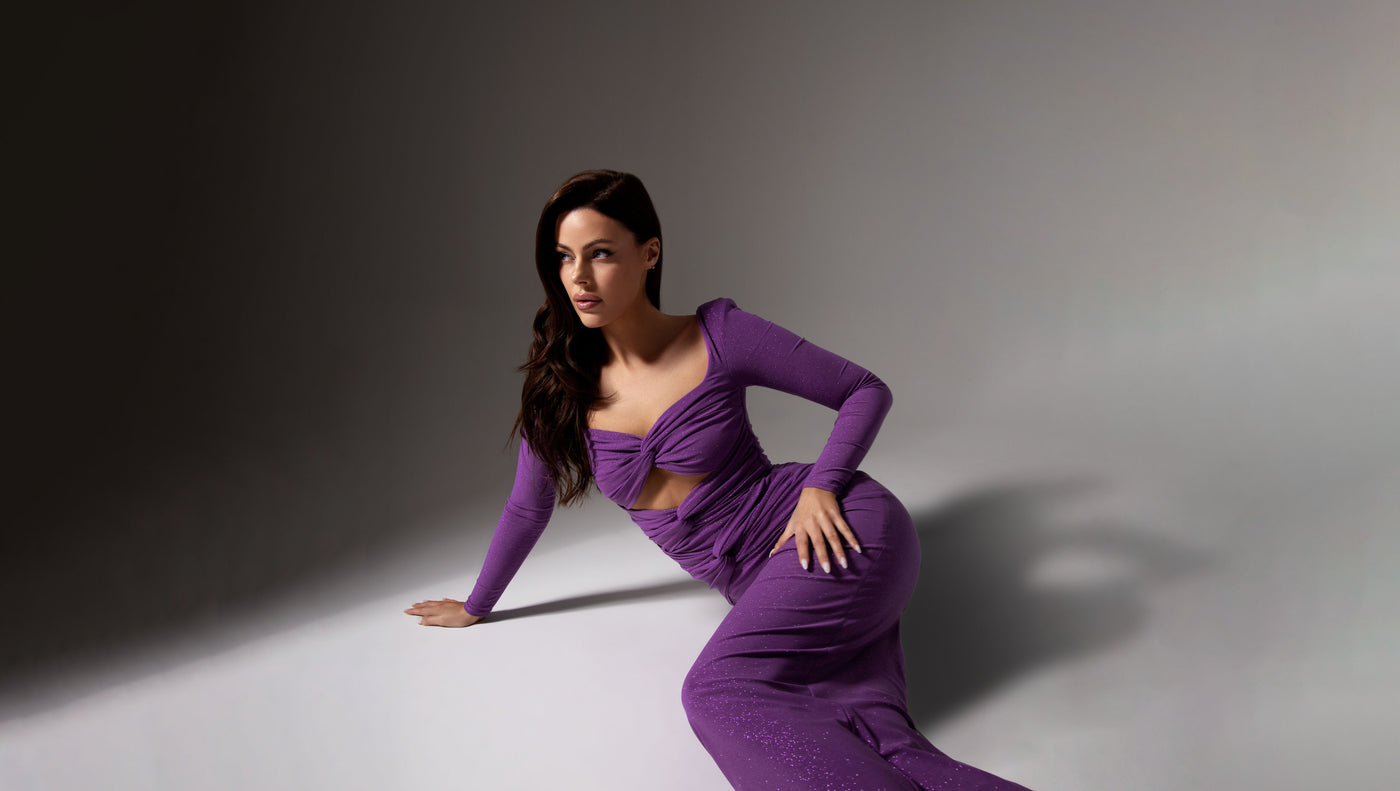 Woman in a purple dress posing against a gray background
