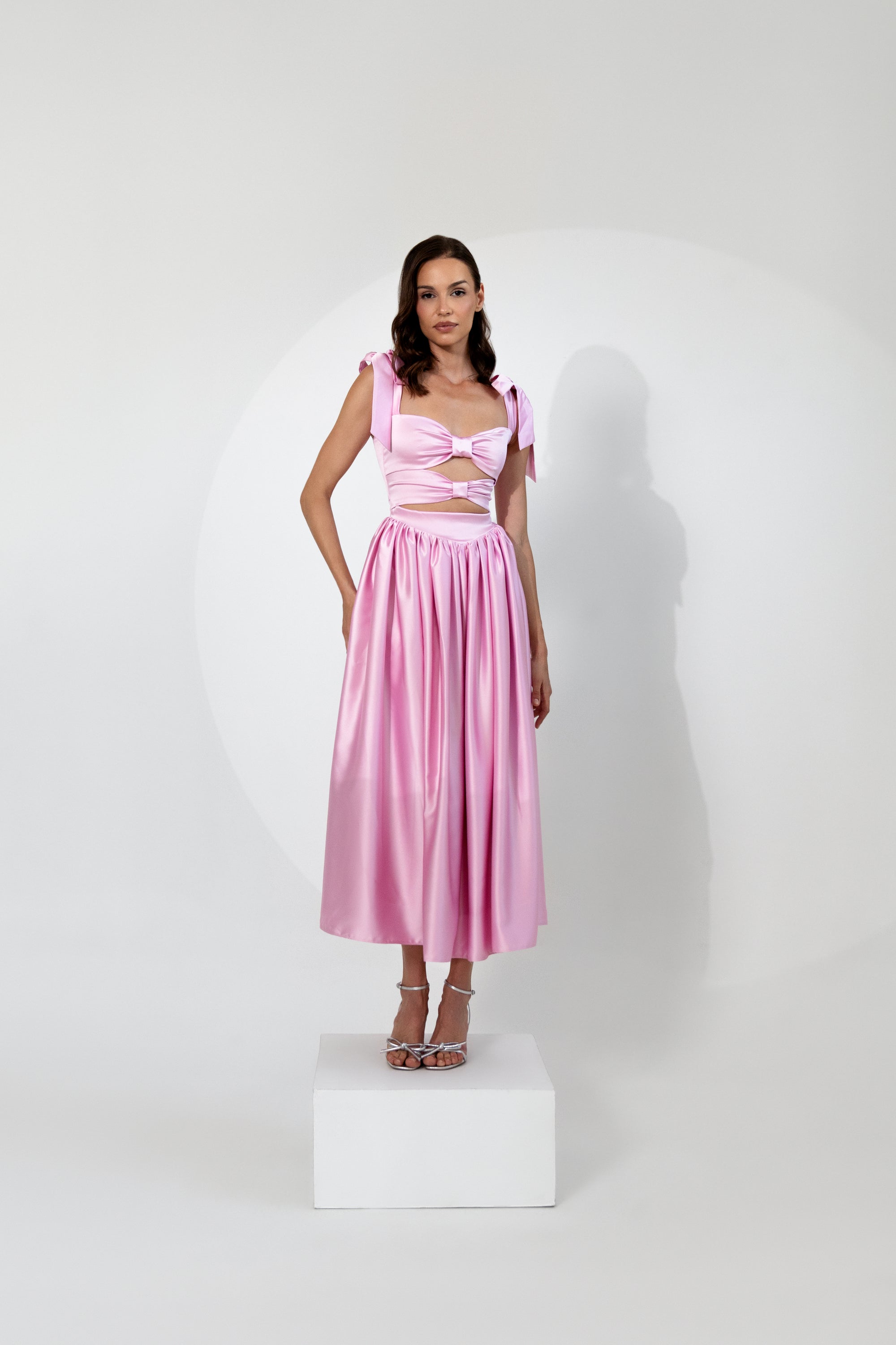 Elegantes rosafarbenes Satin-Kleid mit Cut-Out-Details, Schleifen-Trägern und fließendem, ausgestelltem Rock.